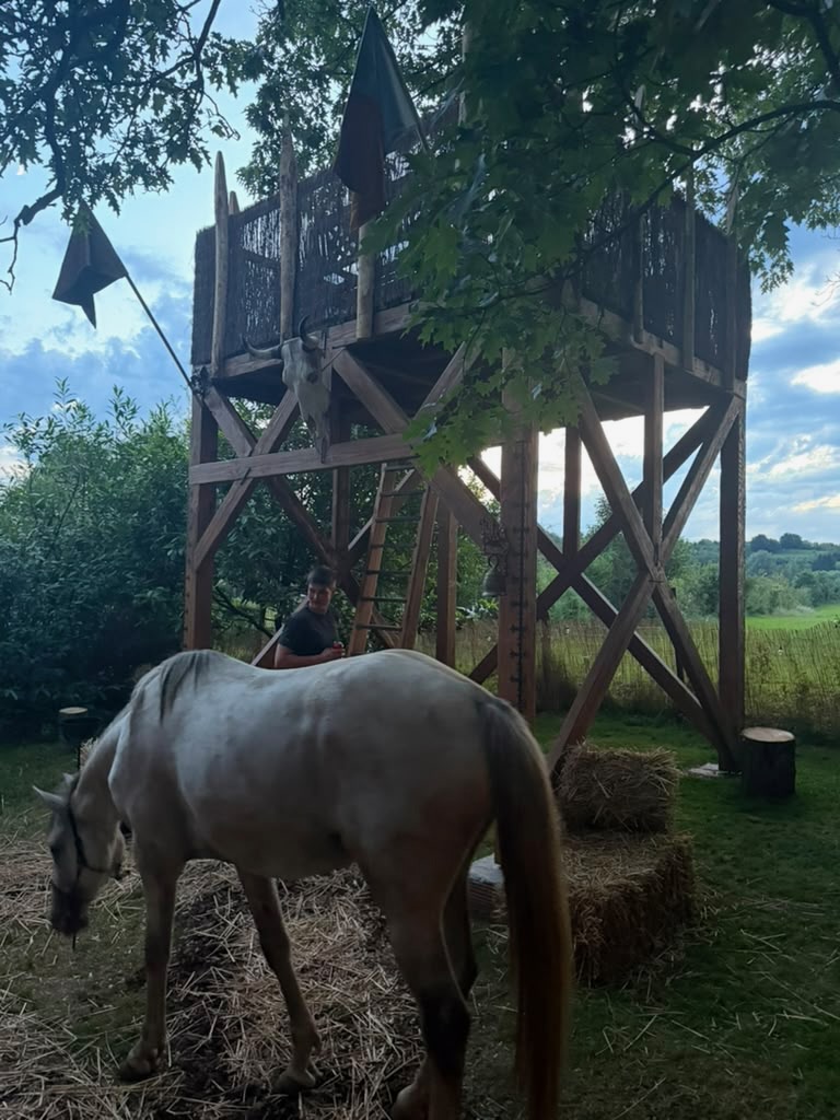 Weißes Pferd vor einem hölzernen Wachturm in der Dämmerung